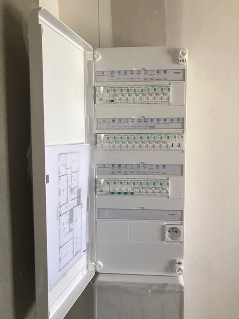 Remplacement d'un tableau électrique Tableau électrique mural avec plusieurs rangées de disjoncteurs et circuits repérés.