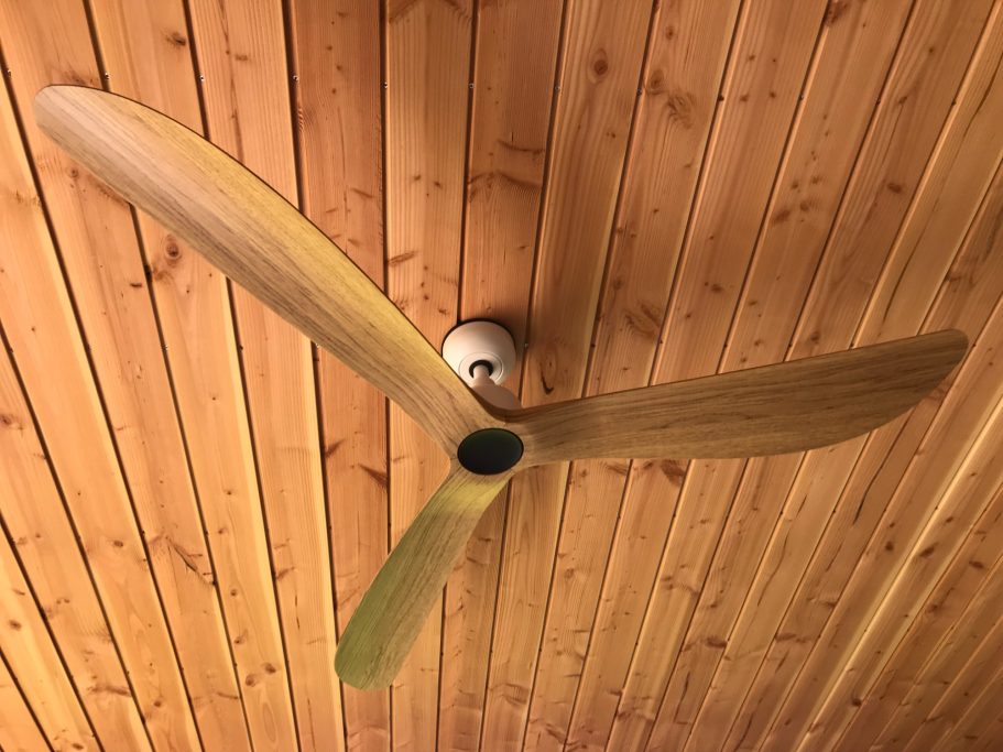 Installation d'un ventilateur de plafond Ventilateur de plafond avec pales effet bois installé sous un plafond en lambris.