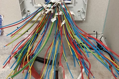 Câbles électriques sortant d’un tableau électrique en cours d’installation pour une extension de maison.