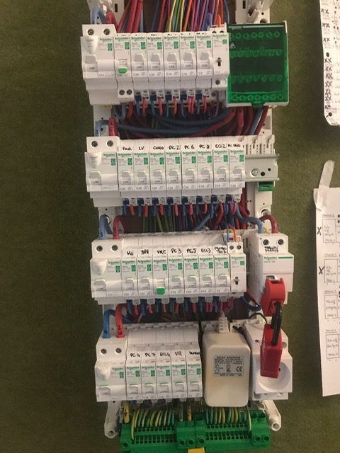 Vérification et intervention sur un tableau électrique Tableau électrique avec plusieurs rangées de disjoncteurs et câblage apparent.